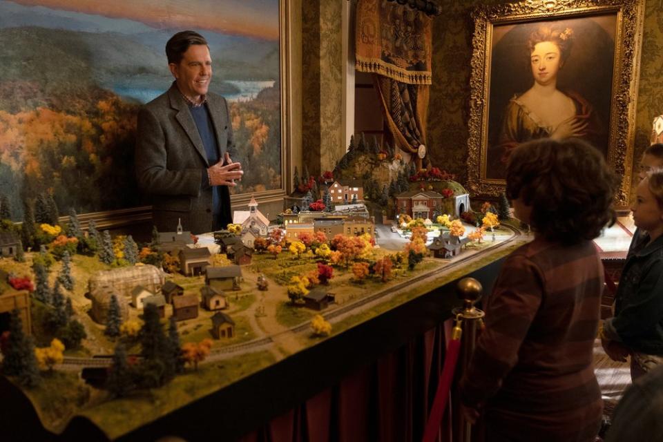 Ed Helms as Nathan Rutherford stands behind a scale model of a town