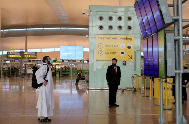 A man wearing a face mask looks at empty departures boards at Josep Tarradellas Barcelona-El Prat Airport, during a partial lockdown as part of a 15-day state of emergency to combat the coronavirus disease (COVID-19) outbreak