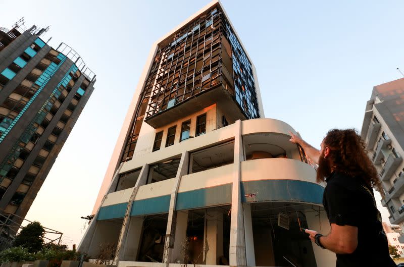 Shady Rizk, a survivor wounded during last year's Beirut port blast, points at the damaged office where he was working at the moment of the blast, in Beirut