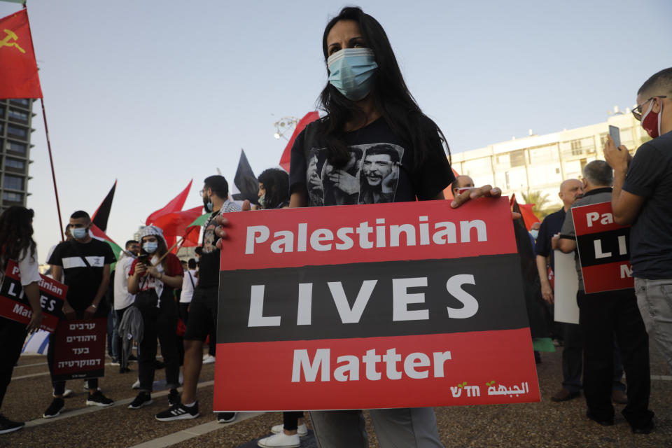 A woman holds a sign during a rally against Israel plans to annex parts of the West Bank, in Tel Aviv, Israel, Saturday, June 6, 2020. (AP Photo/Sebastian Scheiner)