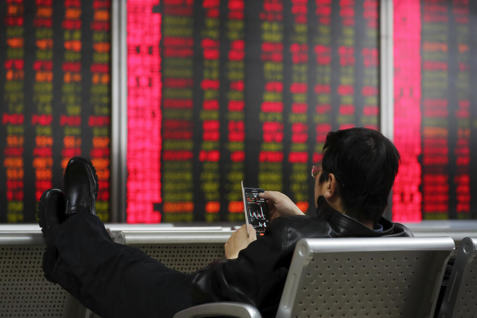 A man checks stock prices through his smartphone at a brokerage house in Beijing, Friday, Dec. 6, 2019. Shares swung higher in Asia on Friday after a wobbly day of trading on Wall Street as investors awaited a U.S. government jobs report and kept an eye out for developments in China-U.S. trade talks. (AP Photo/Andy Wong)