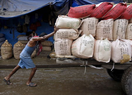 A labourer pushes a handcart loaded with sacks containing tea packets, towards a supply truck at a wholesale market in Kolkata, India, June 26, 2015. REUTERS/Rupak De Chowdhuri