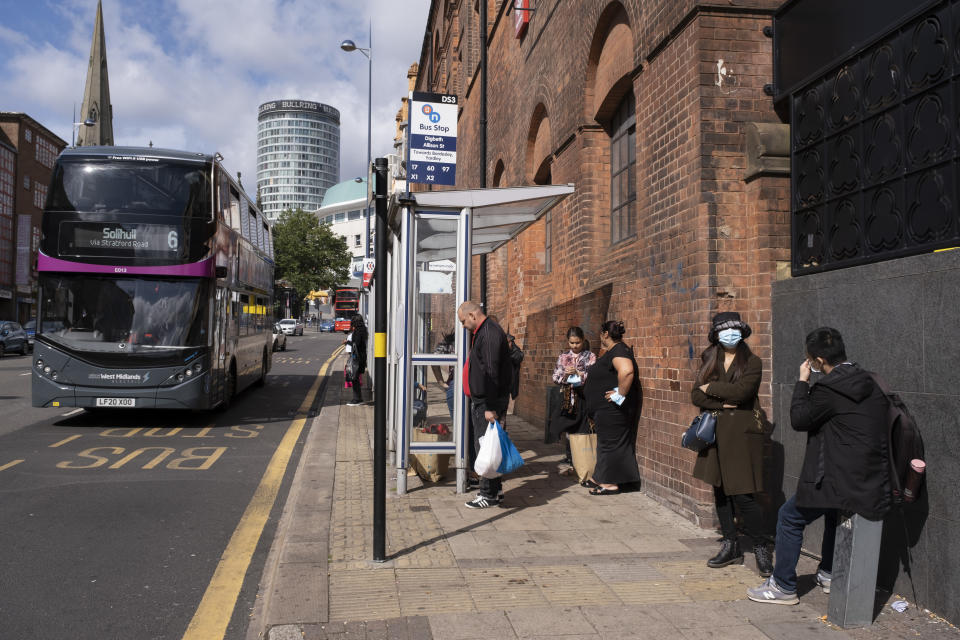 As numbers of Covid-19 cases in Birmingham have dramatically risen in the past week, increased lockdown measures have been announced for Birmingham and other areas of the West Midlands, people wearing face masks waiting at a bus stop a s abus to Solihull passes just outside the shopping district in the city centre on 12th September 2020 in Birmingham, United Kingdom. With the rule of six also being implemented the Birmingham area has now be escalated to an area of national intervention, with a ban on people socialising with people outside their own household, unless they are from the same support bubble. (photo by Mike Kemp/In Pictures via Getty Images)