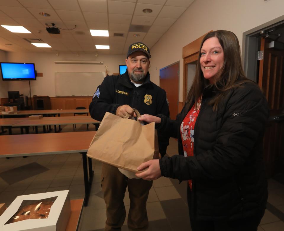 City of Poughkeepsie Police officer sergeant Mike Longbard accepts desserts donated byBreanna Thatcher of the Dutchess County Office of Probation for the police department's Thanksgiving dessert drive at the City of Poughkeepsie Public Safety Building on November 22, 2022.