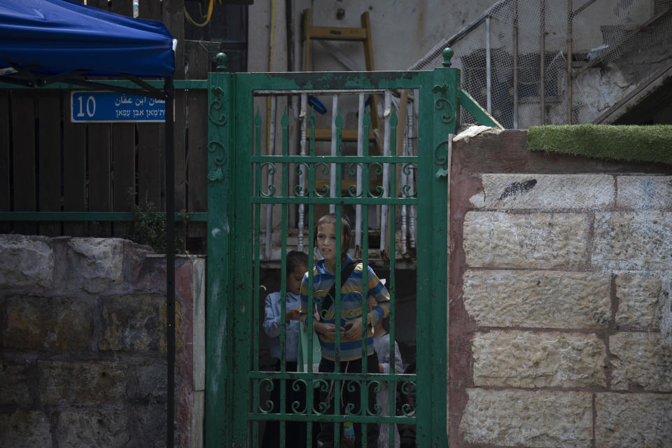 A child peers from the front gate of a Palestinian house occupied by Israeli settlers, days ahead of a court verdict that may forcibly evict Palestinian families from their homes in the Sheikh Jarrah neighborhood of Jerusalem, Friday, May 7, 2021. Dozens of Palestinian families in east Jerusalem are at risk of losing their homes to Jewish settler groups following a decades-long legal battle. The threatened evictions have sparked weeks of protests and clashes in recent days, adding to the tensions in Jerusalem. (AP Photo/Maya Alleruzzo)