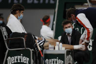 Egor Gerasimov of Belarus is treated for an ankle injury in the first round match of the French Open tennis tournament against Spain's Rafael Nadal at the Roland Garros stadium in Paris, France, Monday, Sept. 28, 2020. (AP Photo/Alessandra Tarantino)