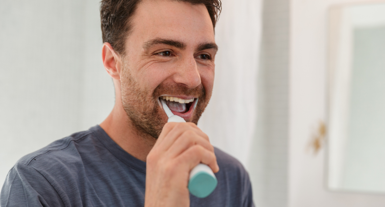 amazon toothbrush sale, white man brushing teeth with electric toothbrush wearing grey t-shirt, Something to smile about: Save $50 on the Oral-B Power iO Series 6 Electric Rechargeable Toothbrush on Amazon Canada