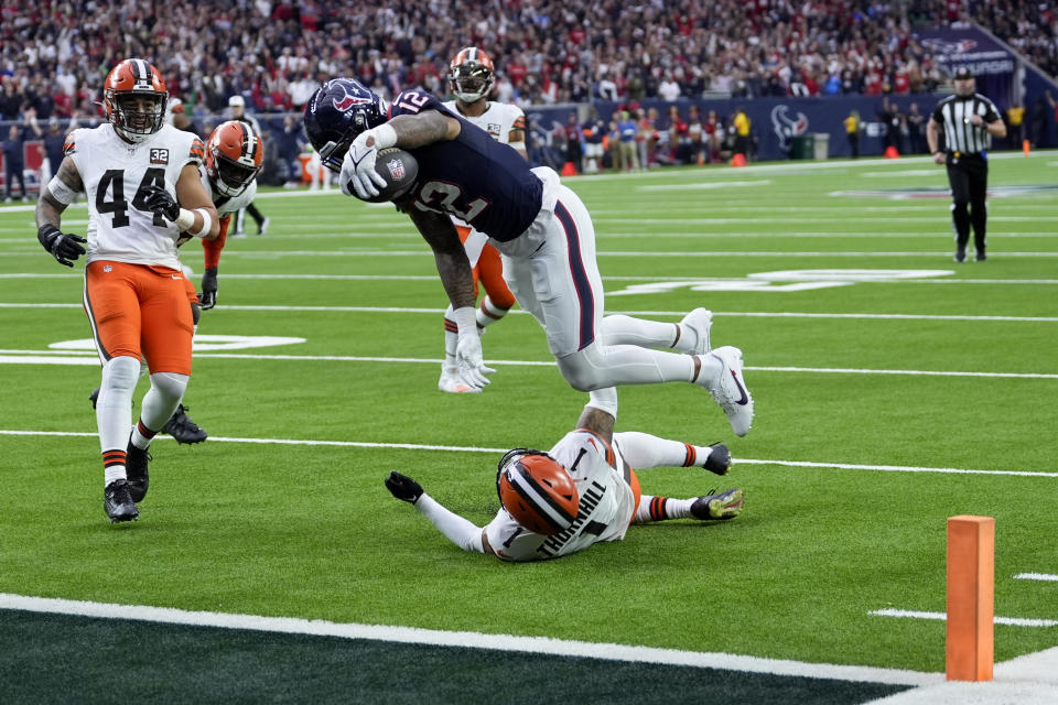 Houston Texans wide receiver Nico Collins scores over Cleveland Browns safety Juan Thornhill during the first half of an NFL wild-card playoff football game Saturday, Jan. 13, 2024, in Houston. (AP Photo/David J. Phillip)