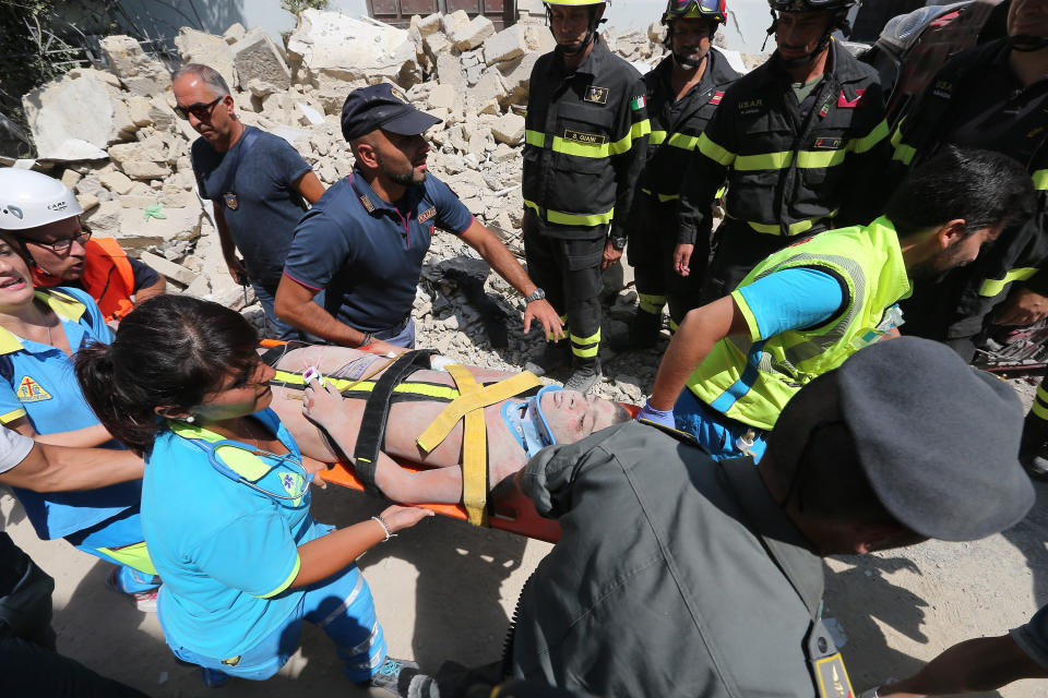 <p>Italian emergency workers evacuate on a stretcher a boy who was was trapped by rubble, in Casamicciola Terme, on the Italian island of Ischia, on August 22, 2017, after an earthquake hit the popular Italian tourist island off the coast of Naples, causing several buildings to collapse overnight. (Photo: Marco Cantile/NurPhoto via Getty Images) </p>