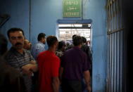 Palestinians wait to cross into Jerusalem at an Israeli checkpoint in the West Bank town of Bethlehem, in this July 7, 2013 file photo. REUTERS/Ammar Awad/Files