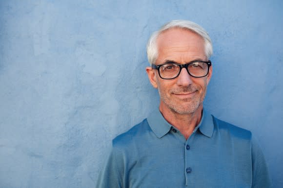 Senior male in glasses against a blue background.