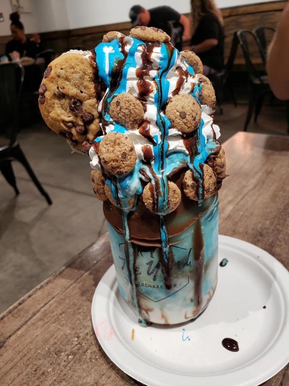 Over-the-top milkshake with whipped cream, chocolate syrup, cookie pieces and a large cookie