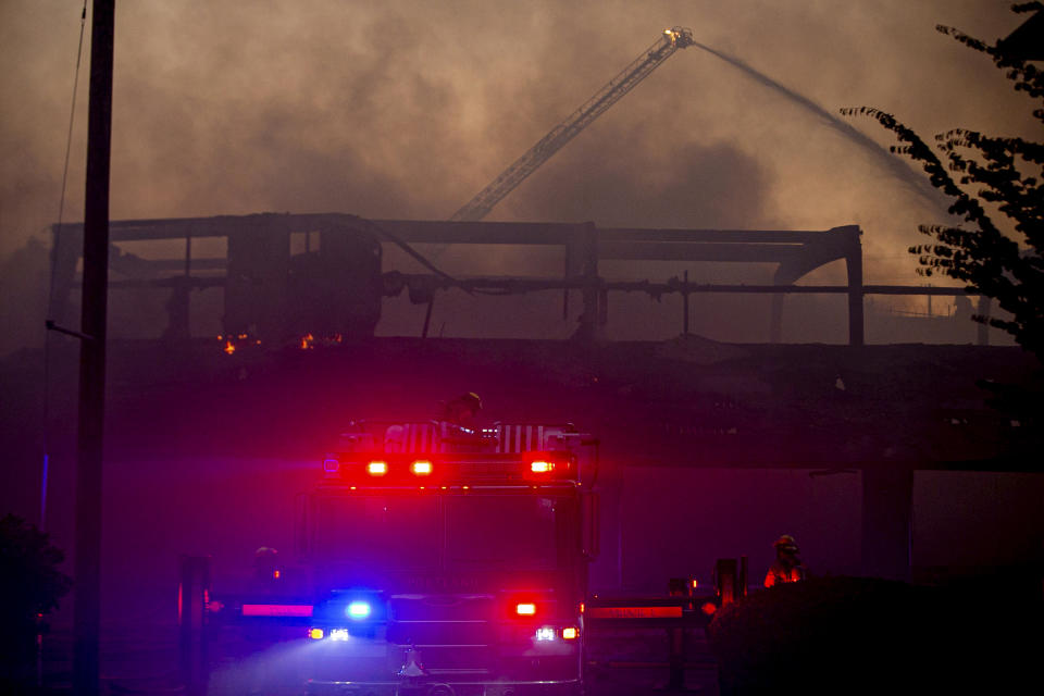 A 4-alarm grass fire destroyed two buildings, burned several others and prompted evacuations Monday, Aug. 26, 2019, in Northeast Portland. Lt. Rich Chatman, a Portland Fire & Rescue spokesman, said a townhouse and old fitness center were destroyed by the wind-driven blaze. Four other townhouses were burned, and the Lumberyard Bike Park was also damaged, Chatman said. About 50 cars parked in an area lot were destroyed, as well. No one was seriously hurt. (Mark Graves/The Oregonian via AP)