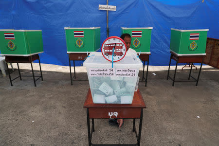 Election worker sits next to a ballot box during the general election at a polling station in Bangkok, Thailand, March 24, 2019. REUTERS/Athit Perawongmetha