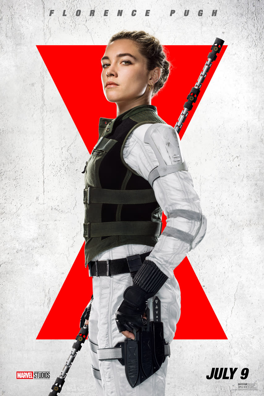  Florence Pugh wears a white suit and black bullet-proof vest, and holds a large staff.