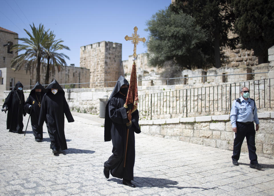 Armenian clergymen with face masks and gloves walk towards the Church of the Holy Sepulchre, traditionally believed by many Christians to be the site of the crucifixion and burial of Jesus Christ, in Jerusalem's old city after the traditional Holy Fire ceremony was called off amid coronavirus, Saturday, April 18, 2020. A few clergymen on Saturday marked the Holy Fire ceremony as the coronavirus pandemic prevented thousands of Orthodox Christians from participating in one of their most ancient and mysterious rituals at the Jerusalem church marking the site of Jesus' tomb.(AP Photo/Ariel Schalit)