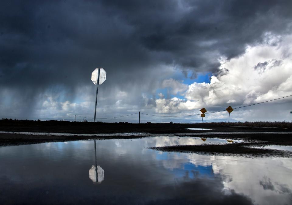 Storm clouds are reflected in a puddle as they approach Undine Road and Wing Levee Road in French Camp on March 2, 2018.