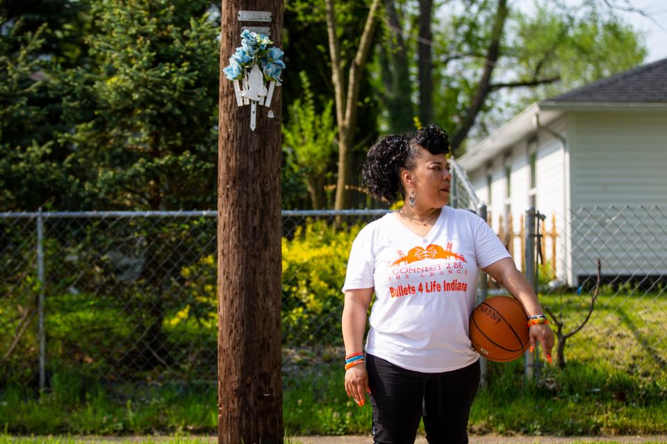 Loria Perez talks about losing her son Kelvin Stanford Jr. while holding a basketball he owned near a memorial she setup Wednesday, May 11, 2022 near her former home in South Bend. 