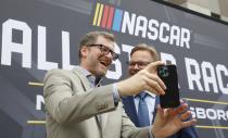 Dale Earnhardt Jr., left, laughs with Speedway Motorsports President and CEO Marcus Smith as they record a video after a press conference announcing that the NASCAR All-Star Race will be held at North Wilkesboro Speedway in May 2023, on the steps of the N.C. Museum of History in Raleigh, N.C., Thursday, Sept. 8, 2022. (Ethan Hyman/The News & Observer via AP)