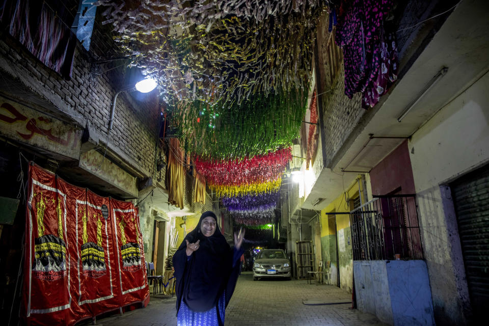 A woman walks on a street under decorations a day ahead of the holy month of Ramadan, in the Imbaba neighborhood of Giza, April 23, 2020. Muslims around the world are trying to maintain the cherished rituals of Islam holiest month during the coronavirus pandemic. (AP Photo/Nariman El-Mofty)
