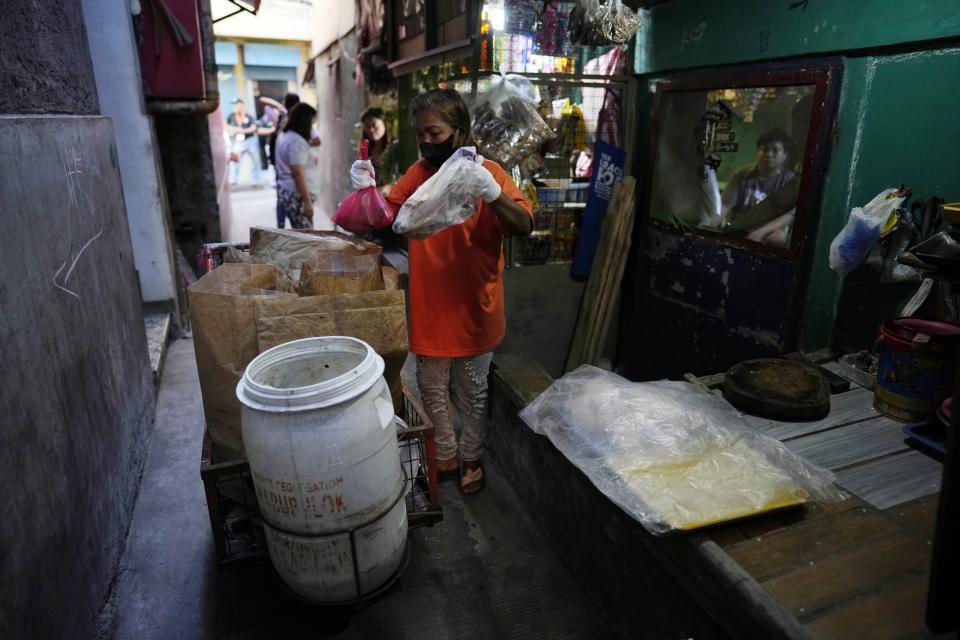 Marilene Capentes collects segregated garbage and places it on her cart along the streets of Malabon, Philippines on Monday Feb. 13, 2023. Capentes, who is 47, said the trash used to be all mixed together — and heavy — until a local environmental nonprofit started asking residents to separate it a few years ago. (AP Photo/Aaron Favila)