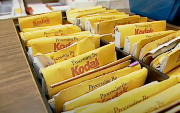 Rows of vintage Kodak film envelopes on a counter, suggesting a scene from a photo development lab