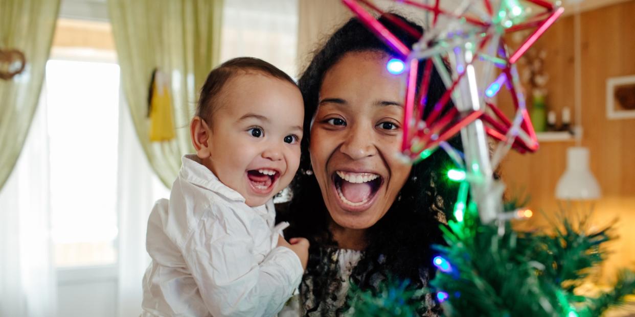 mom and toddler smiling at Christmas tree star making Christmas unforgettable