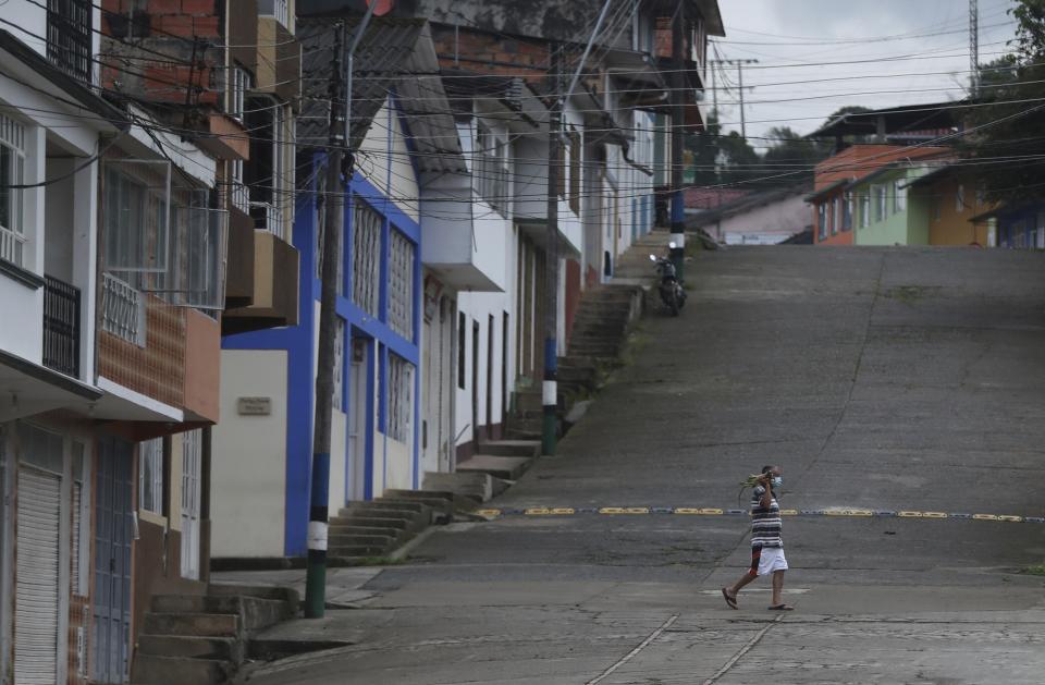 Wearing a mask to curb the spread of the new coronavirus, a resident walks on a street in Campohermoso, Colombia, Thursday, March 18, 2021. According to the Health Ministry, Campohermoso is one of two municipalities in Colombia that has not had a single case of COVID-19 since the pandemic started one year ago. (AP Photo/Fernando Vergara)