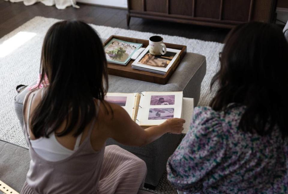 Dee Iraca, left, and her sister, Becca Webster look at childhood photos in Davidson, N.C., on Wednesday, May 10, 2023.