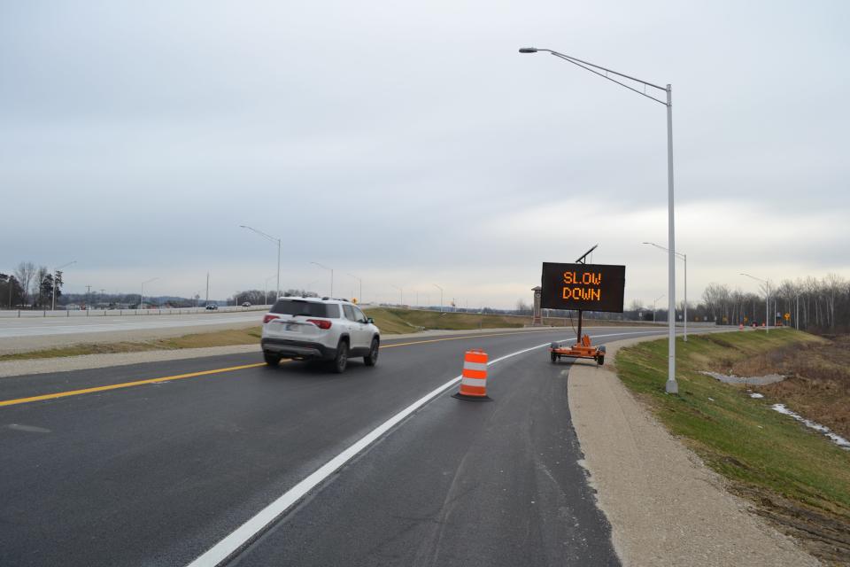 A vehicle drives by an electric sign at the I-69 and Ind. 39/Morton Avenue/Southview Drive interchange. The sign warns drivers of a sharp curve and asks them to slow down as they make their approach.