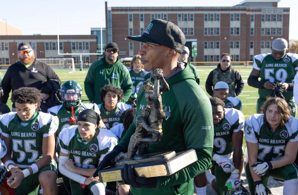 Long Branch Coach Chad King accepts the game trophy on behalf of his team. Long Branch defeats Red Bank Regional 41-20 in Thanksgiving Day football game in Long Branch NJ on November 23, 2023.