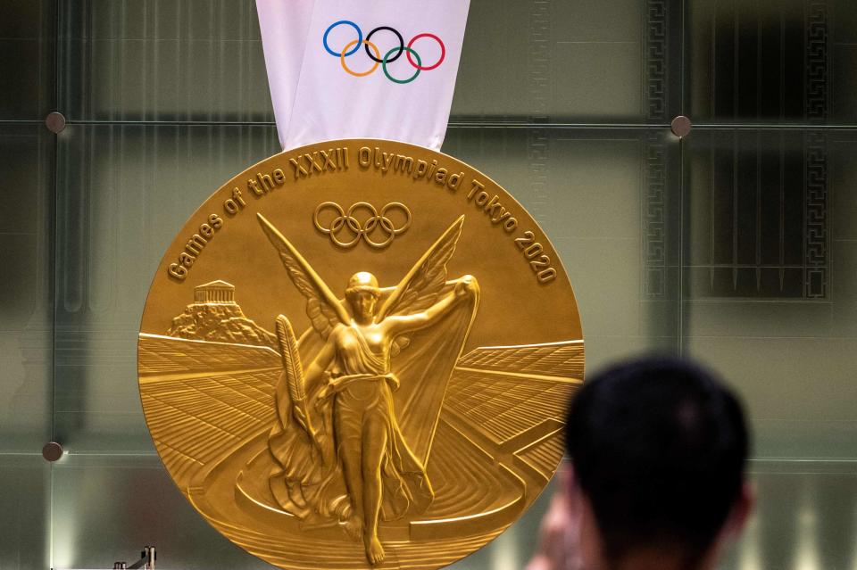 A man takes pictures of a large-scale reproduction of the Tokyo 2020 Olympic Games gold medal as part of the Olympic Agora event at Mitsui Tower in Tokyo.