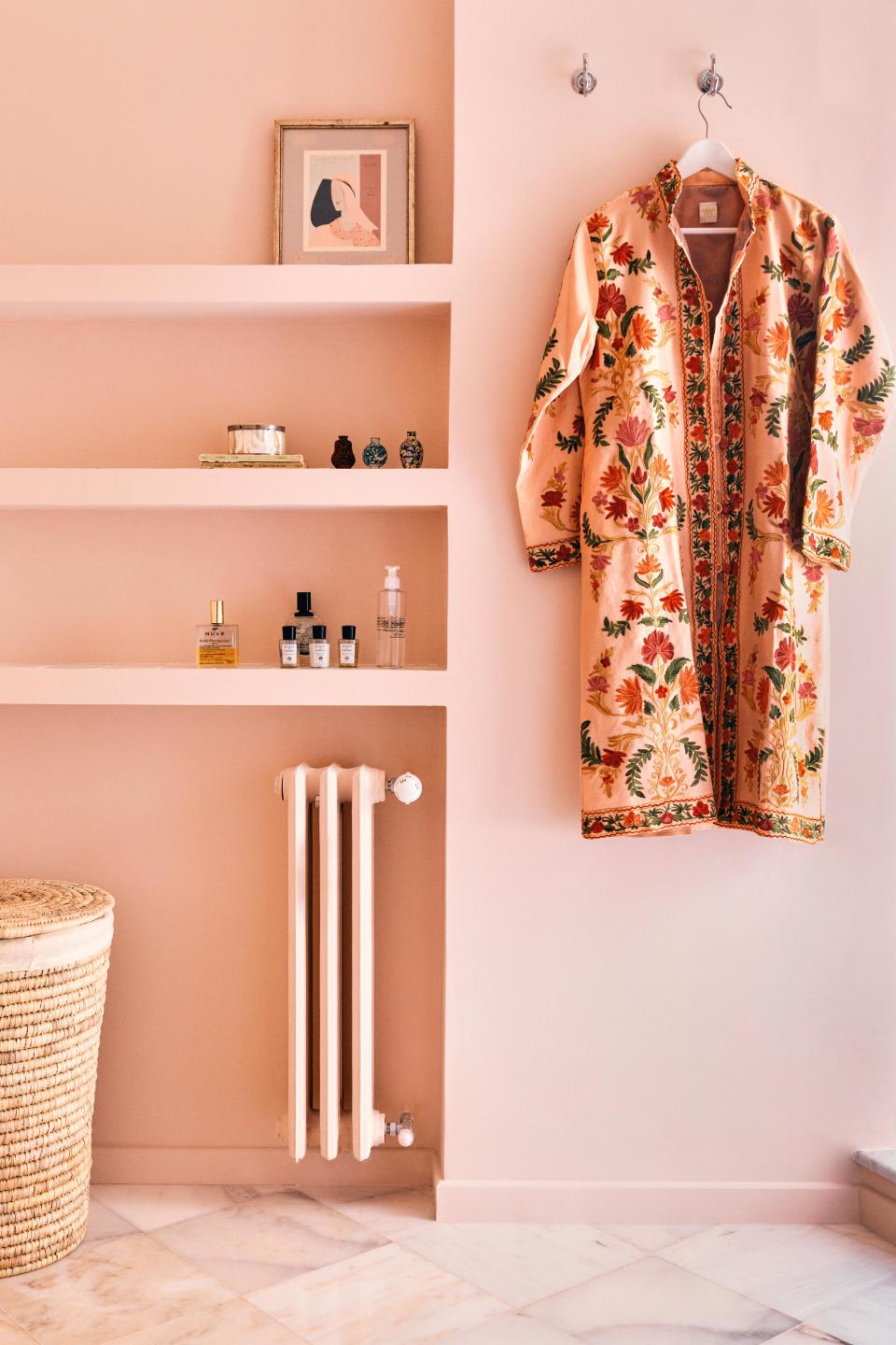 Miniature apothecary jars line the shelves in the primary bathroom. The brilliant kaftan-style coat, acquired from Lol Roma, happily doubles as decor.