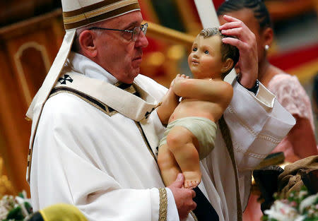 Pope Francis holds a statuette of baby Jesus during the traditional midnight mass in St. Peter's Basilica on Christmas Eve at the Vatican December 24, 2017. REUTERS/Tony Gentile