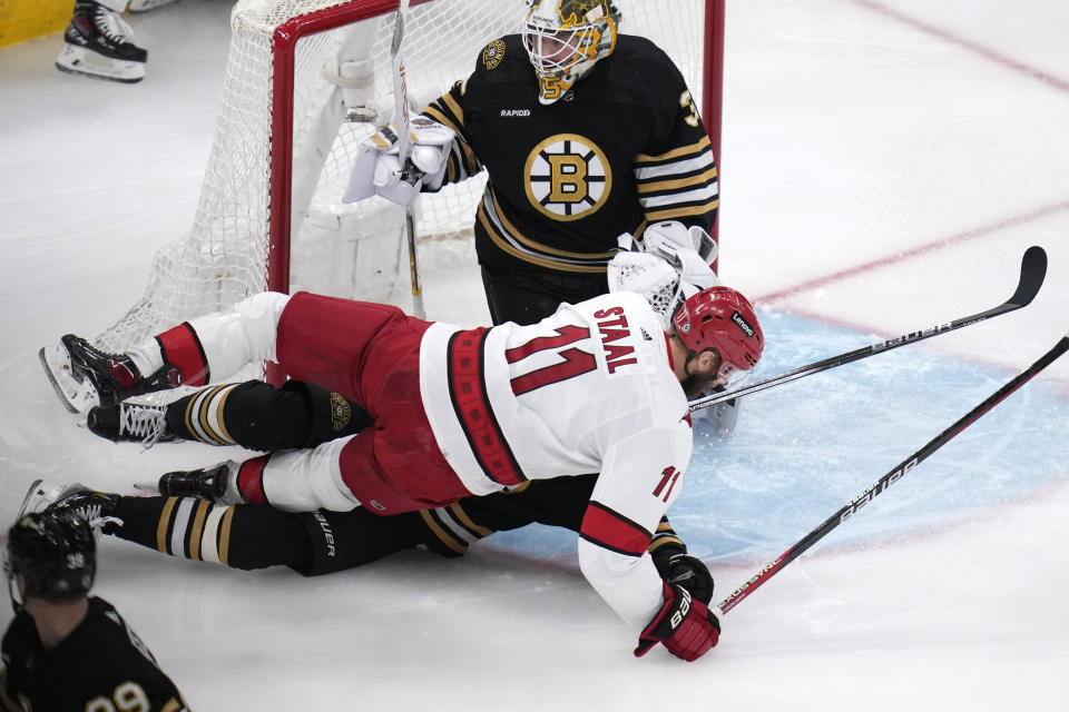 Carolina Hurricanes center Jordan Staal (11) collides with Boston Bruins center Trent Frederic, bottom, in front of goaltender Linus Ullmark during the first period of an NHL hockey game Wednesday, Jan. 24, 2024, in Boston. (AP Photo/Charles Krupa)