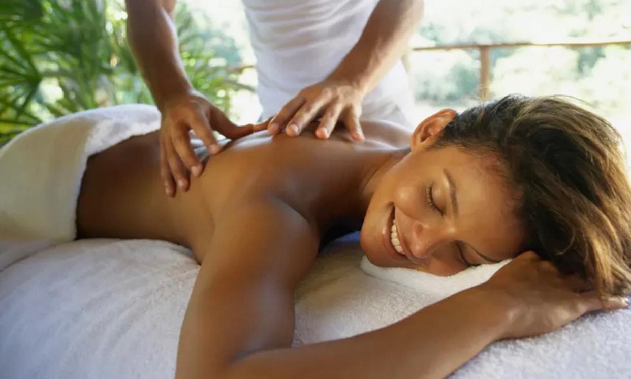 Black woman smiling while getting a back massage.