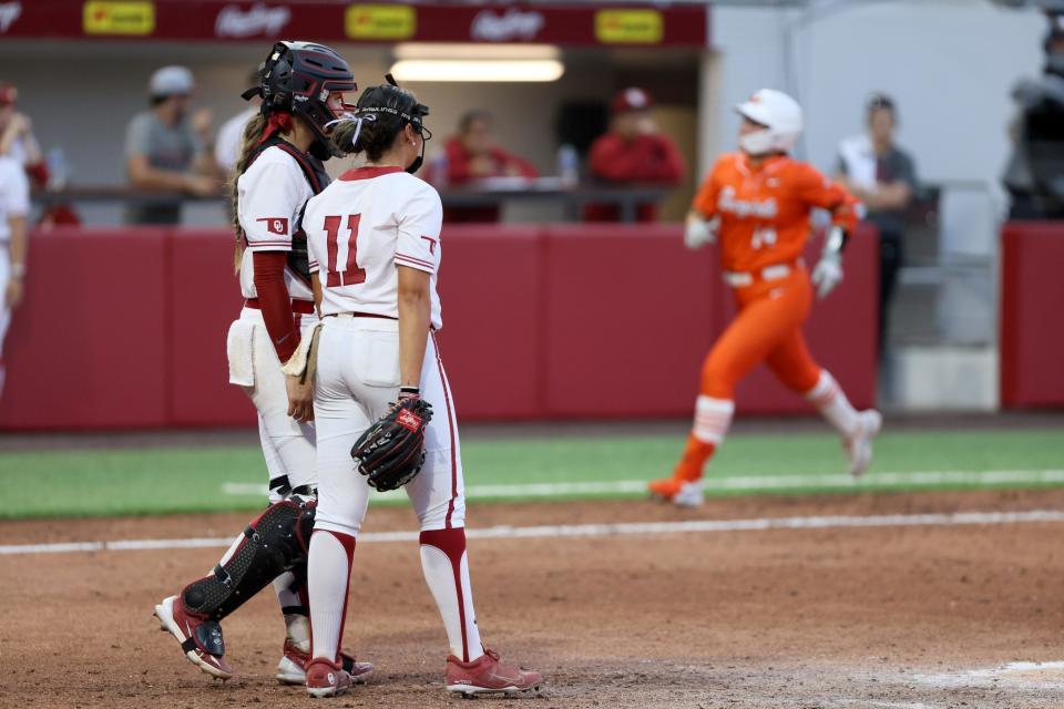 Oklahoma catcher Kinzie Hansen (9) and pitcher Kierston Deal (11) watch as Oklahoma State infielder Karli Godwin (14) runs home after hitting a home run in the fifth inning of a Bedlam softball game between the University of Oklahoma Sooners (OU) and the Oklahoma State Cowgirls (OSU) at Love's Field in Norman, Okla., Friday, May 3, 2024. Oklahoma State won 6-3.