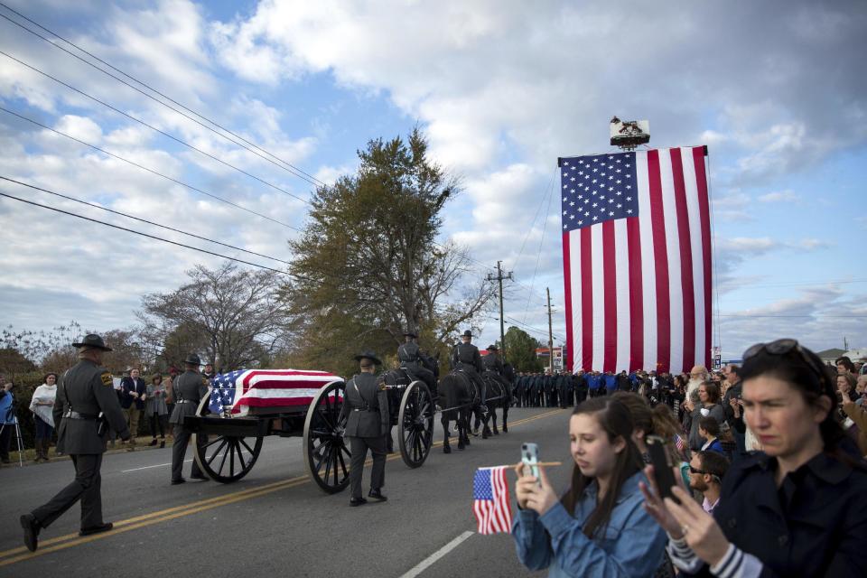 People watch as procession for Americus police officer Nicholas Smarr passes on the way to the burial site at Oak Grove Cemetery, Sunday, Dec. 11, 2016, in Americus, Ga. Smarr and Jody Smith, an officer with Georgia Southwestern State University, were shot and killed while responding to a domestic violence call. (AP Photo/Branden Camp)