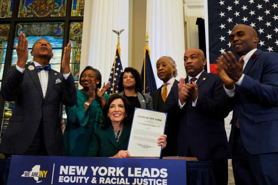 New York Gov. Kathy Hochul holds up signed legislation creating a commission for the study of reparations in New York on Dec. 19, 2023, in New York City. Gov. Hochul was joined by Rev. Al Sharpton, various members of New York government leadership and influential community members six months after state lawmakers passed the bill and three years after California became the first state to create a reparations task force. (Photo by Michael M. Santiago/Getty Images)