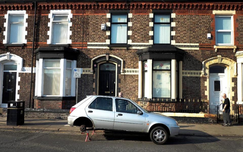 Men look at a car with it’s back wheels missing as it stands outside a row of terraced houses in Liverpool northern England, May 8 , 2016. (Phil Noble/REUTERS)