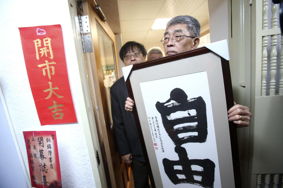 Lam Wing-kee, one of five shareholders and staff at the Causeway Bay Book shop in Hong Kong, holds his congratulatory gift, Chinese calligraphy that reads: ''Freedom'' at the door of his new book shop on the opening day in Taipei, Taiwan, Saturday, April 25, 2020. The part-owner of the Hong Kong bookstore specializing in texts critical of China’s leaders reopened his shop in Taiwan on Saturday after fleeing Hong Kong due to legal troubles, saying he was grateful for the opportunity to make China's Communist rulers “less than happy." The red slogan reads: ''Opening Lucky." (AP Photo/Chiang Ying-ying)
