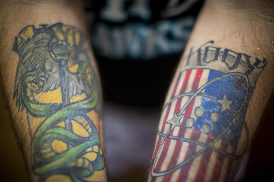 Robert Decker shows his tattoos to honor the U.S. Navy service of both of his sons, Kyle and Kody, at his home in Norfolk, Va., on Tuesday, March 14, 2023. Decker's youngest son, Kody, committed suicide in October 2022 while stationed at Norfolk Naval Station. (AP Photo/John C. Clark)
