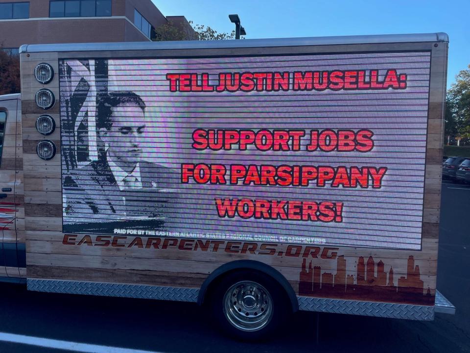 A truck is seen in Parsippany before a council meeting, with an Eastern Atlantic State Regional Council of Carpenters logo and a large video sign with an image of Musella and a message.