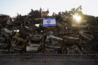 An Israeli flag is placed on a pile of charred vehicles burned in the bloody Oct. 7 cross-border attack by Hamas militants, outside the town of Netivot, southern Israel, Sunday, Jan.7, 2024. (AP Photo/Ohad Zwigenberg)