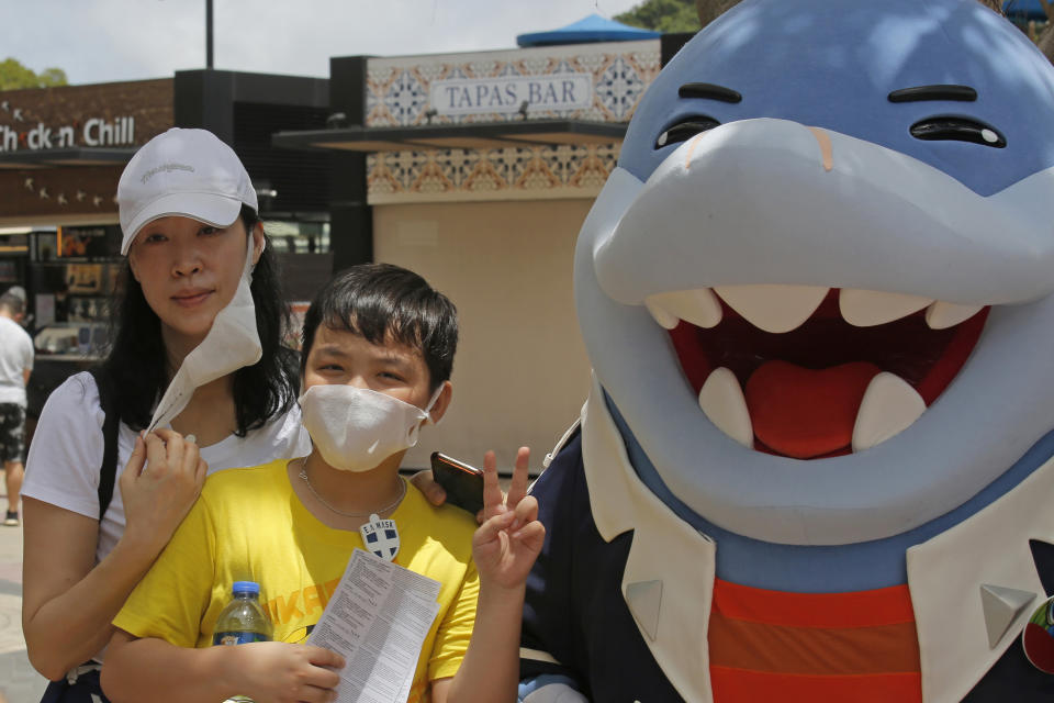 A woman takes off her face mask for a photograph at the Ocean Park amusement park in Hong Kong, Saturday, June 13, 2020. Hong Kong's Ocean Park reopened Saturday after nearly four months of closure due to the coronavirus pandemic. The animal and nature-themed attraction combines pandas, penguins, roller coasters and other rides, and has been a Hong Kong icon since its opening in 1977. (AP Photo/Kin Cheung)