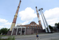 A woman walks by the closed Wujek coal mine in Katowice, Poland, Saturday, July 4, 2020. The coronavirus has ripped through Poland's coal mines, where men descend deep underground in tightly packed elevators and work shoulder-to-shoulder. The virus hot spots, centered in the southern Silesia region, have paralyzed an already-troubled industry, forcing many to stay home from work and triggering a three-week closure of many state-run mines. (AP Photo/Czarek Sokolowski)