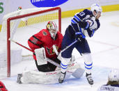 Winnipeg Jets' Pierre-Luc Dubois (13) takes a shot to the chest as he attempts to screen Ottawa Senators goaltender Matt Murray (30) during the third period of an NHL hockey game Wednesday, April 14, 2021, in Ottawa, Ontario. (Sean Kilpatrick/The Canadian Press via AP)