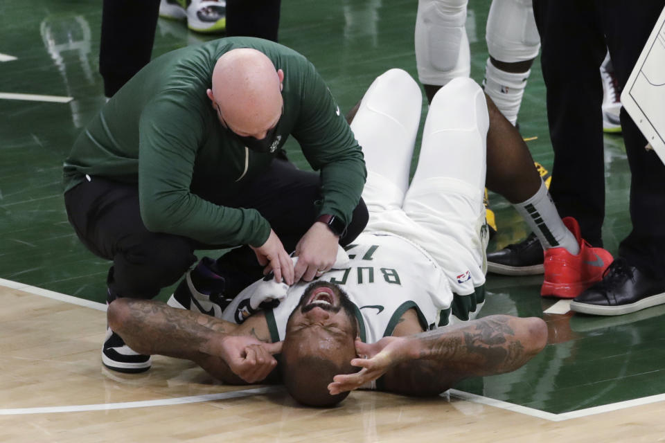 Milwaukee Bucks' P.J. Tucker is checked on by a trainer after suffering an injury during the second half of the team's NBA basketball game against the Washington Wizards on Wednesday, May 5, 2021, in Milwaukee. (AP Photo/Aaron Gash)