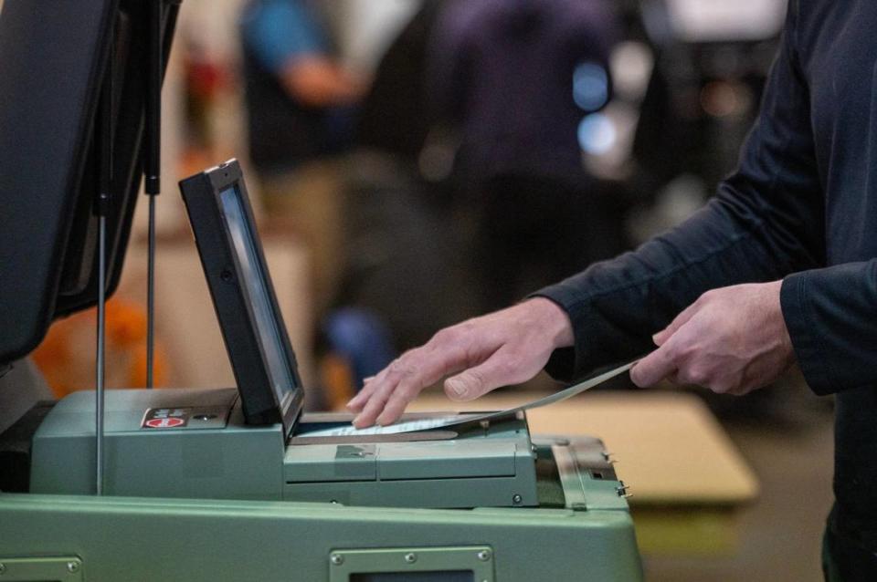 A voter cast their ballot into a voting machine at Asbury United Methodist Church on Tuesday, Nov. 7, 2023, in Prairie Village.