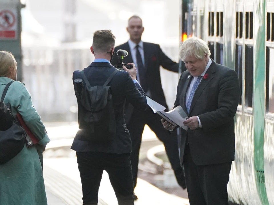 Boris Johnson reads his paperwork as he stands next to a ‘Green Train’ at Glasgow Central station that he visited after arriving at another platform by train from London (PA)